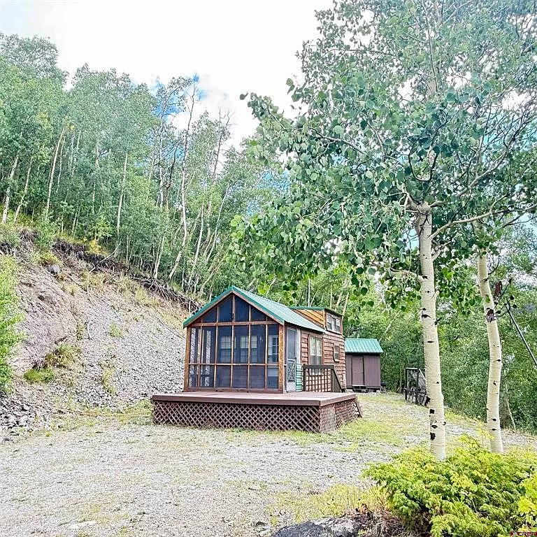 The Champion cabin with green metal roof, set against an aspen hillside